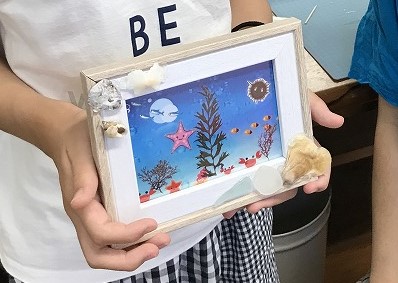 貝で装飾した写真立てを持っている画像