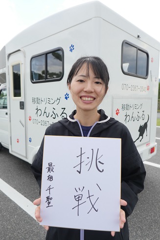 「わんふる」の車の前で「挑戦」と書かれた紙を持っている最相さんの画像